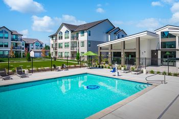 A swimming pool in front of a building with a black fence around it.